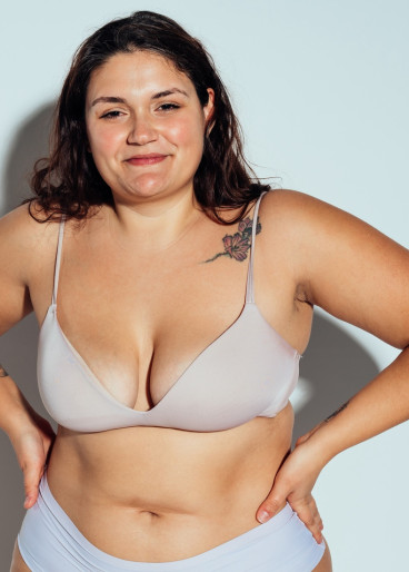 Stämmige, kräftige Frau, beide Hände abgestützt in der Hüfte.